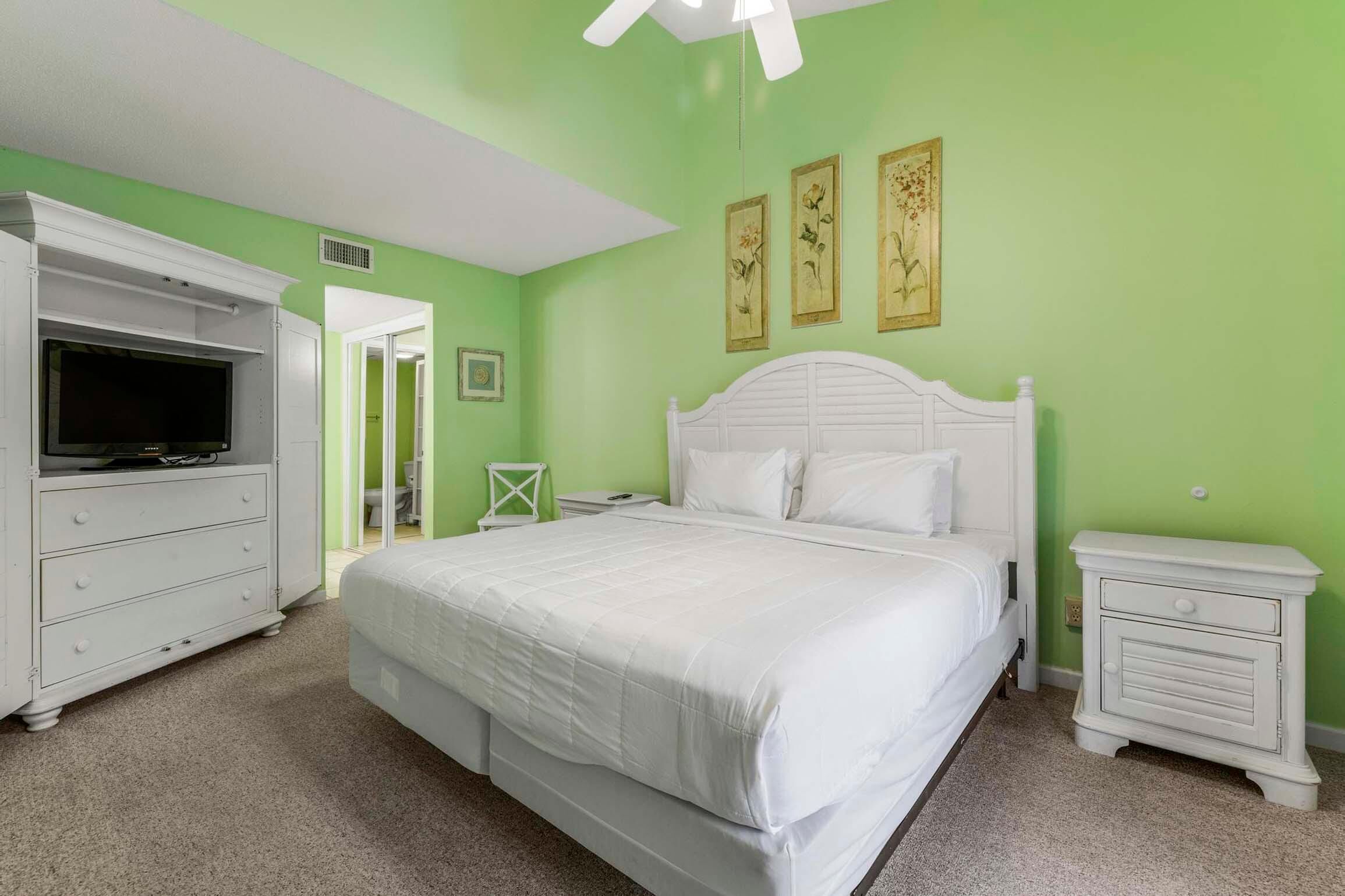 A bedroom with a bed, a dresser, a nightstand, and a television.