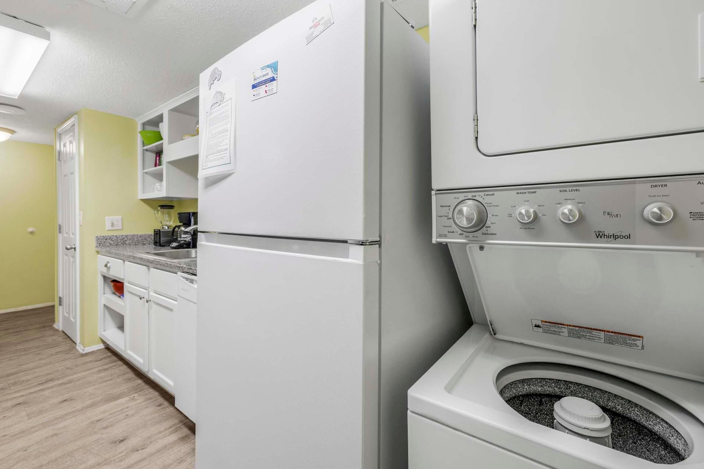 A compact kitchen with a built-in washer and dryer, white cabinets, and a microwave.