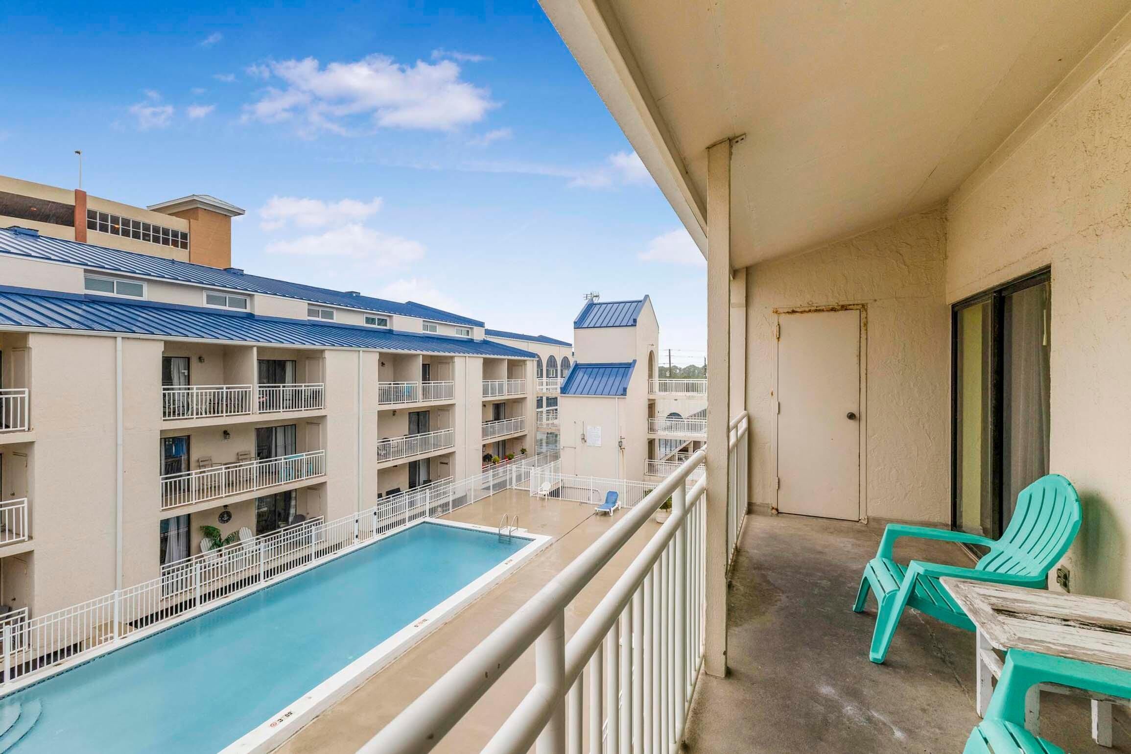 A hotel balcony with a pool, multiple floors, and a view of other buildings.