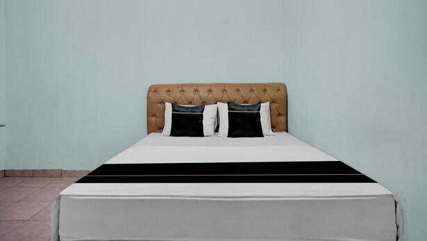 A bed with a tufted headboard, two black and white pillows, and a white and black bedspread. - Hotel O near Universitas Medan Area (Medan)