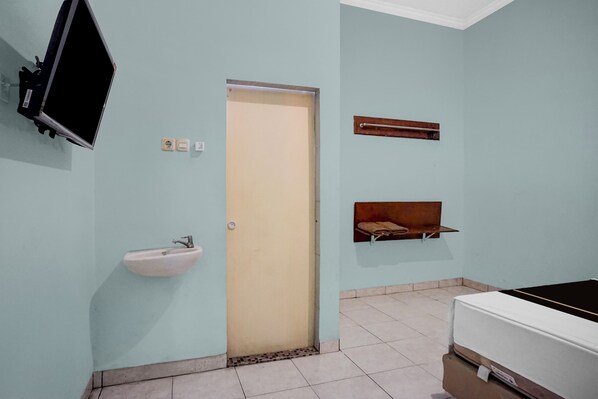 A room with a bed, a sink, a television, and a door. - Hotel O near Universitas Medan Area (Medan)