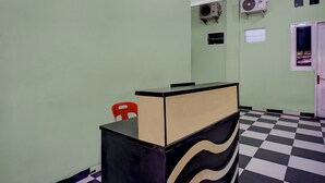 A room with a checkered floor, a reception desk, a red chair, and two air conditioning units on the wall. - Hotel O near Universitas Medan Area (Medan)