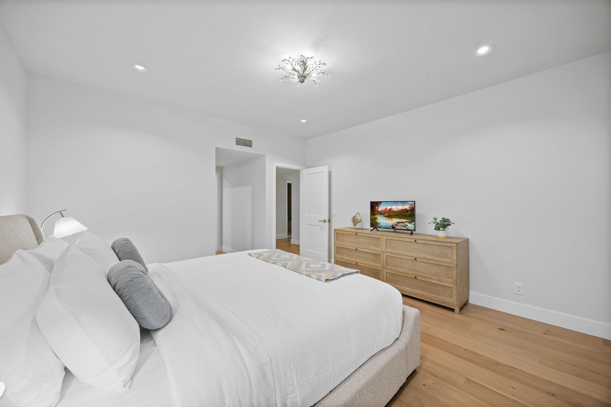 A bedroom with a bed, dresser, and a painting on the wall.