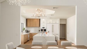 Een moderne keuken met witte kastjes, een houten kookeiland en een hanglamp.