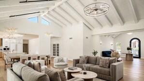 Een ruime woonkamer met een hoge plafond, moderne meubels en een grote kroonluchter.