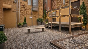 An outdoor seating area with a wooden bench and a wooden platform with string lights. - The Ann Arbor's Nest - Stylish Downtown Stay Near U-M, Dining & Attractions (Ann Arbor)