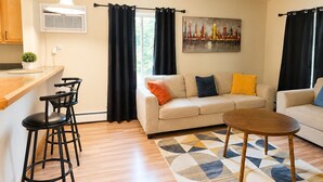 A modern living room with a sofa, coffee table, and bar stools. - The Ann Arbor's Nest - Stylish Downtown Stay Near U-M, Dining & Attractions (Ann Arbor)