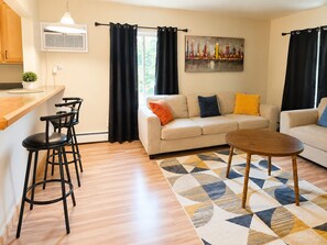 A modern living room with a sofa, coffee table, and bar stools. - The Ann Arbor's Nest - Stylish Downtown Stay Near U-M, Dining & Attractions (Ann Arbor)