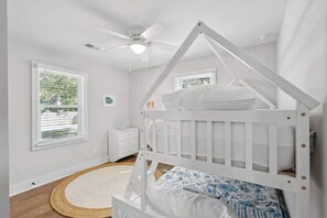 A white bedroom with a bunk bed, a ceiling fan, a bedside table, and a window with blinds. - The Ashley House~10 minutes to downtown Charleston (Charleston)