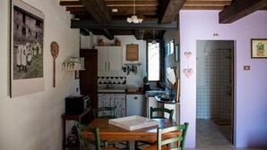 Une cuisine rustique avec des poutres en bois, une table à manger avec des chaises et un comptoir de cuisine sur lequel sont disposés divers objets.