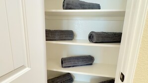 A white closet with multiple shelves holding rolled-up towels. - Cozy Family Retreat (Rosenberg)
