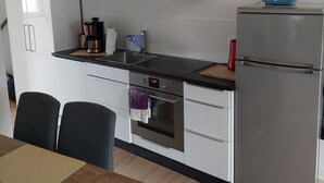 Una cocina moderna con gabinetes blancos, estufa de acero inoxidable, horno empotrado, microondas y refrigerador.