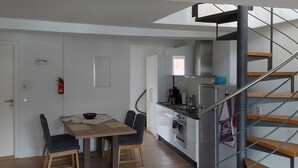 Una cocina moderna con horno integrado y un comedor con mesa y sillas de madera.