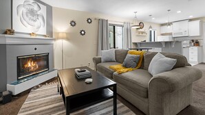 Un salon moderne avec une cheminée, un canapé, une table basse et un coin cuisine.