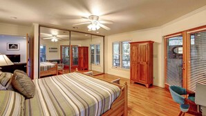 A bedroom with a bed, a wooden wardrobe, a chair, and a ceiling fan. - Casa de Amor - Ocracoke Island (Ocracoke)