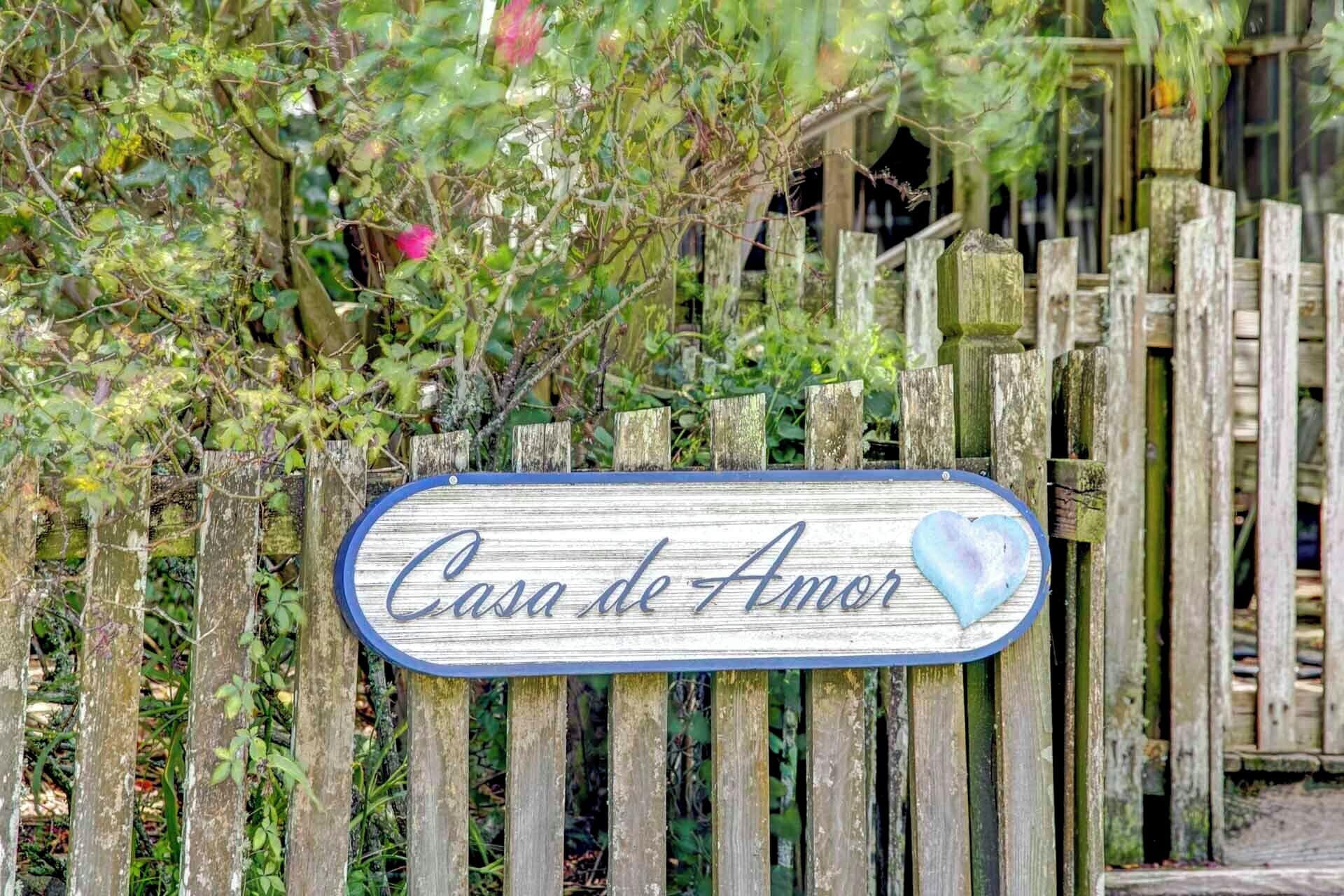 Un letrero de madera con el texto 'Casa de Amor' y un símbolo de corazón.
