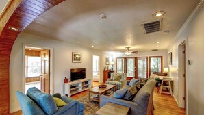 A spacious living room with a large sofa set, a television, and a dining area with a table and chairs. - Casa de Amor - Ocracoke Island (Ocracoke)