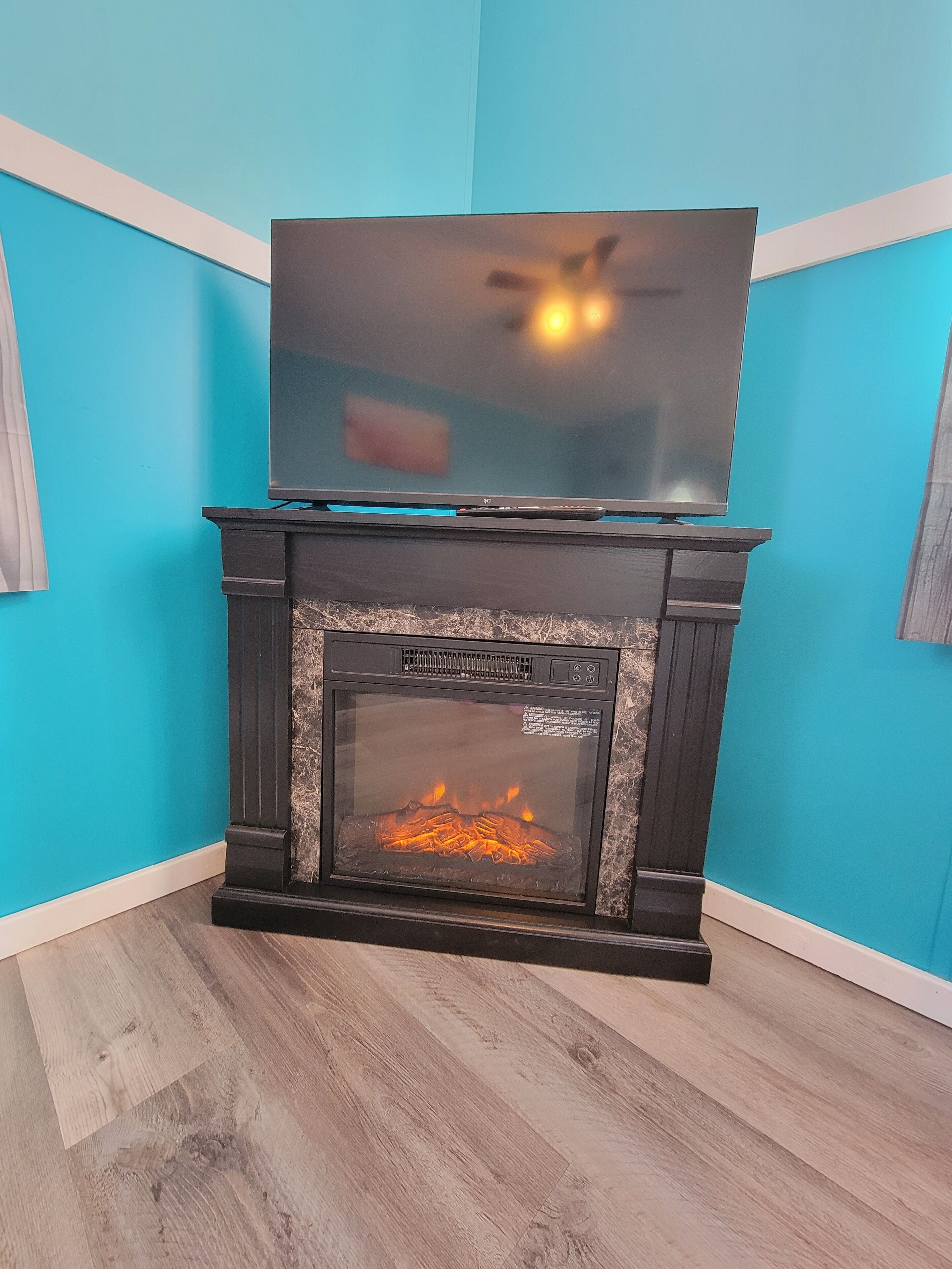 Una chimenea moderna con un televisor de pantalla plana montado encima, frente a una pared color turquesa.
