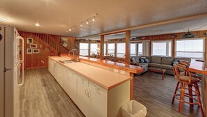 Una cocina compacta con una isla central, paredes de madera y un comedor con vistas.