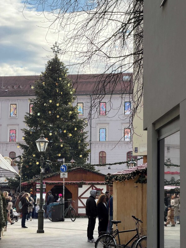 A Christmas tree decorated with lights and ornaments in an urban setting with buildings in the background. - New spacious luxury apartment at Rathausplatz (Augsburg)
