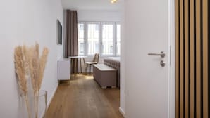 A narrow hallway leading to a room with a bed, a chair, and a table. - Luxury Suite "Augusta Vindelicum" | Rathausplatz Augsburg | A/C | Elevator (Augsburg)