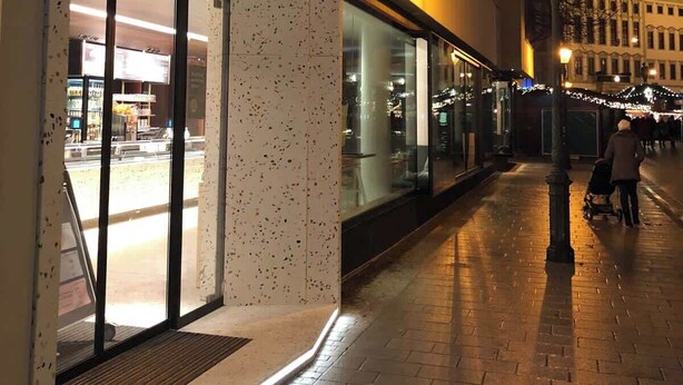 Un edificio con fachada moderna, amplios ventanales y un letrero de neón.