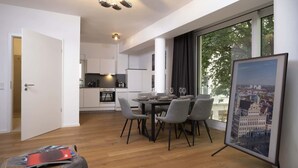 Un apartamento moderno con comedor, cocina y un amplio ventanal con vista a la ciudad.