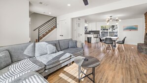 A spacious living area with a gray sectional sofa, a round coffee table, and a dining table with chairs. A ceiling fan and recessed lighting are visible. - Spacious 4BR South Austin Home Minutes to Downtown (Austin)