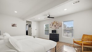 A modern bedroom with a large bed, a wooden floor, a ceiling fan, and a window with blinds. - Spacious 4BR South Austin Home Minutes to Downtown (Austin)