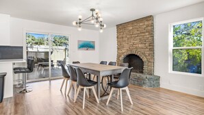 A dining area with a stone fireplace, a wooden table, and black chairs. - Spacious 4BR South Austin Home Minutes to Downtown (Austin)