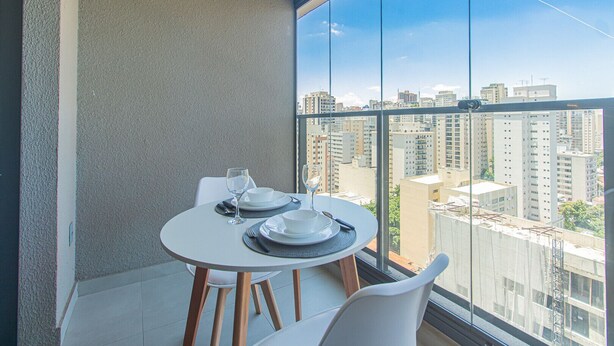 A balcony with a table set for two, overlooking a cityscape with high-rise buildings. - Comfort Near Allianz Parque Sp-p1804b (São Paulo)