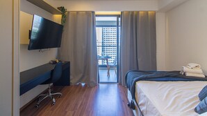 A hotel room with a bed, a desk with a chair, a TV mounted on the wall, and a view of a cityscape through the window. - Comfort Near Allianz Parque Sp-p1804b (São Paulo)
