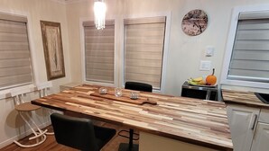A modern kitchen with a wooden island, bar stools, a fruit bowl, and a clock on the wall. - Little House, Rivière Rouge waterfront, 7 minutes from Mont-Tremblant town. (Brébeuf)