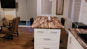 A modern kitchen with a wooden island, white cabinetry, and a patterned rug. - Little House, Rivière Rouge waterfront, 7 minutes from Mont-Tremblant town. (Brébeuf)