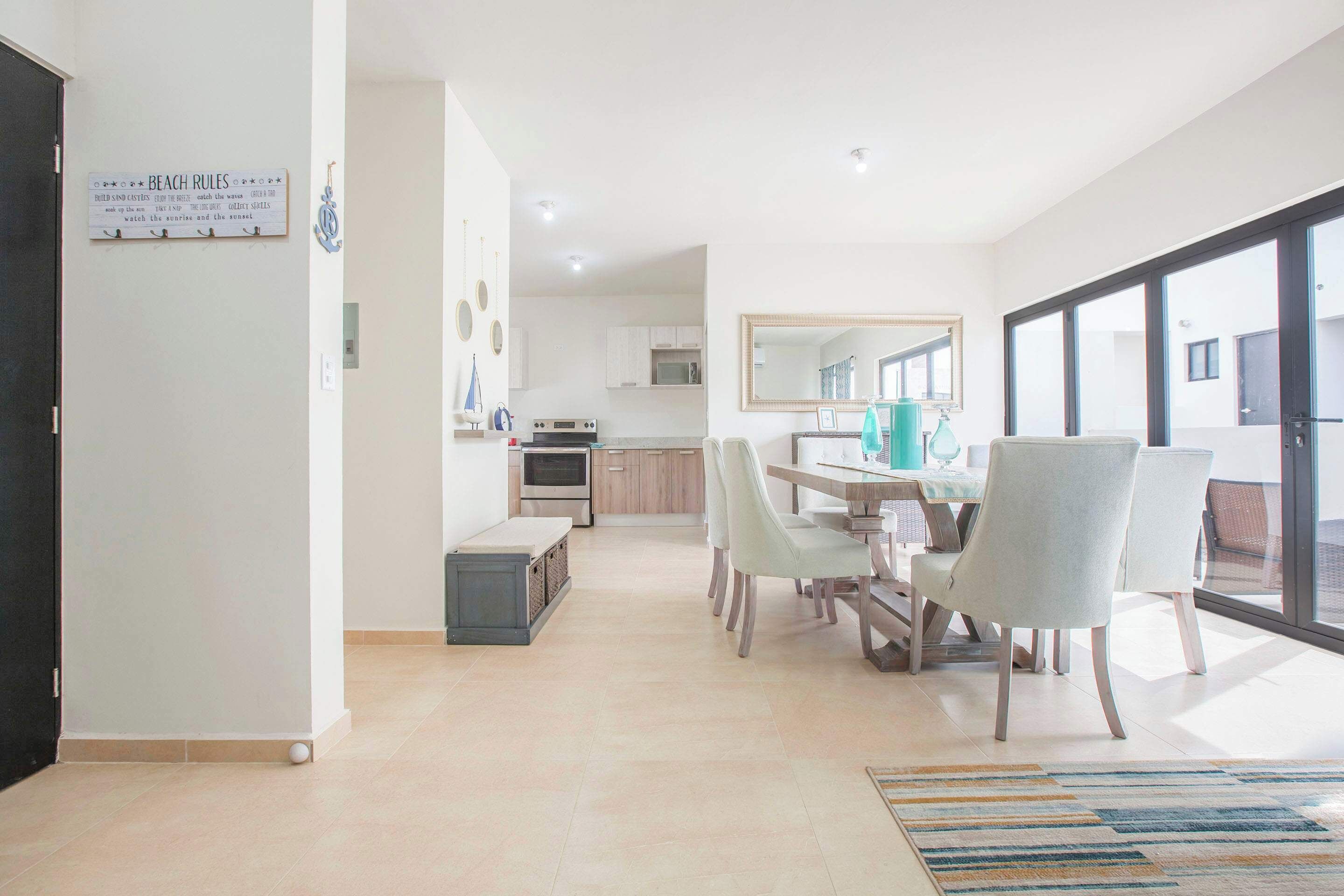Een moderne keuken met witte kasten, een eethoek met een tafel en stoelen, en een groot raam met uitzicht.