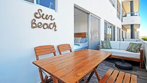 Ein Holztisch mit Stühlen vor einem Gebäude, dessen Schild "Sun Beach" zeigt.