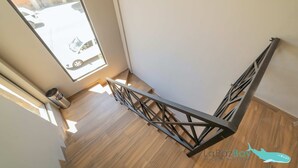 Una scala con ringhiera in metallo, pavimento in legno e vista su un'auto parcheggiata all'esterno.