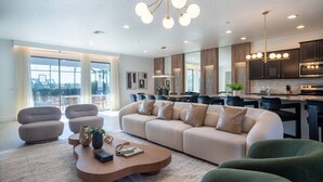 Un salon moderne avec un canapé d’angle, une table basse aux lignes courbes et un coin repas agrémenté d’une grande fenêtre.