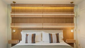 Une chambre à coucher moderne avec une tête de lit en bois, des lampes de chevet et un lit parfaitement fait.
