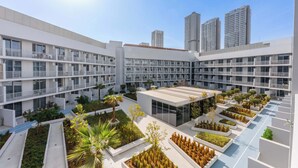 A modern hotel with multiple floors, balconies, and a rooftop garden. - Stayshort - Contemporary Studio With Open Layout in JVC (Dubai)
