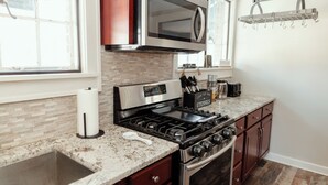 A kitchen with a stainless steel stove, a microwave, and a granite countertop. - Quaint & Cozy Indiana Style (Shelbyville)