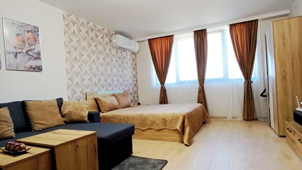 Una habitación moderna y bien iluminada con sofá, una mesita, cama con cabecero y armario.