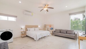 A modern bedroom with a bed, a sofa, a washing machine, and a ceiling fan. - Downtown Apt w/common pool + private terrace (La Paz)
