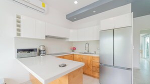 A modern kitchen with white cabinetry, a stainless steel refrigerator, a coffee maker, and a built-in oven. - Downtown Apt w/common pool + private terrace (La Paz)