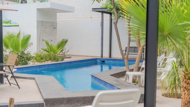 A swimming pool with a tiled edge, surrounded by palm trees and lounge chairs. - Downtown Apt w/common pool + private terrace (La Paz)