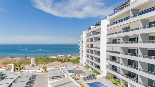 Un hotel a più piani con balconi affacciati su una spiaggia e l'oceano.