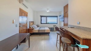 Una camera da letto moderna con un letto, un comodino e vista mare attraverso un'ampia finestra.