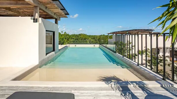 A modern outdoor swimming pool with a clear view of the surrounding greenery and a building with a minimalist design. - Exquisitely Decorated 2 BD Retreat in Tulum (Tulum)