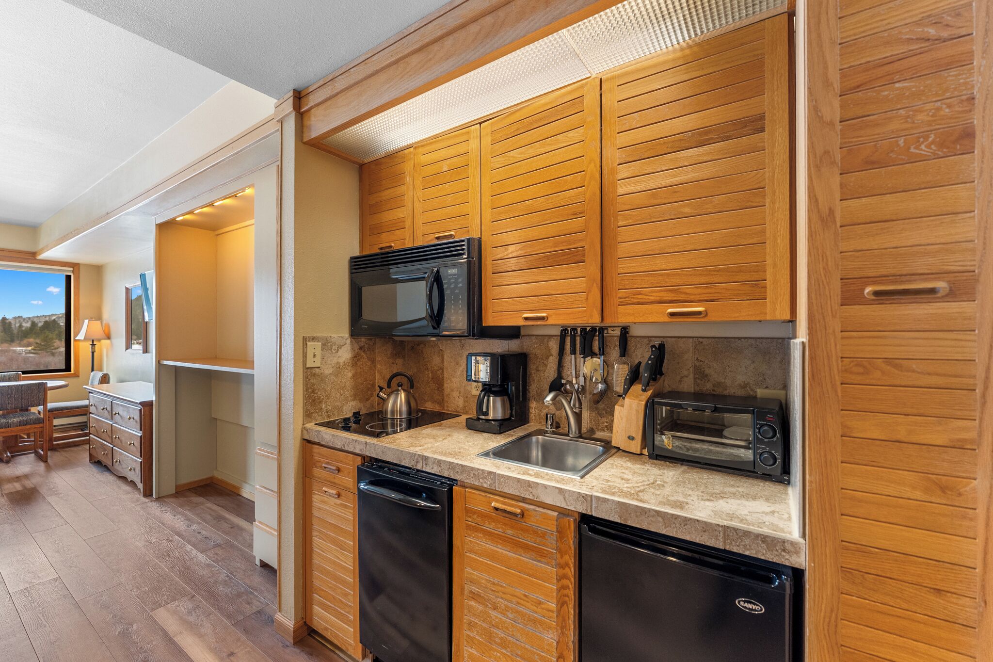 A modern kitchen with wooden cabinets, a microwave, a toaster, and a dishwasher.
