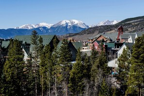 A mountain town with snow-capped peaks in the background, surrounded by dense forests and a mix of traditional and modern buildings. - Slopeside #2736 (Keystone)